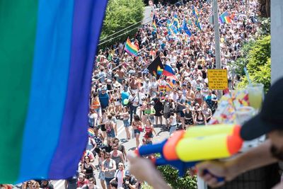 High angle view of people with rainbow flags marching on city street