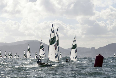 Sailboats in sea against sky