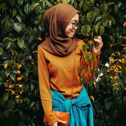 Smiling woman standing against plants