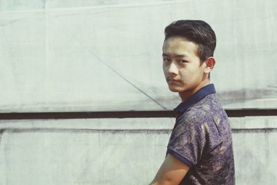 Portrait of boy standing against wall