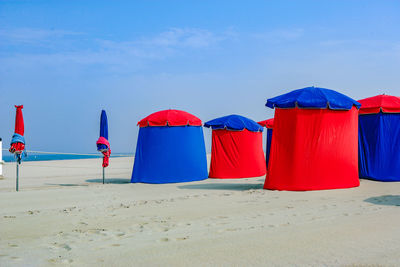 Multi colored umbrellas on beach against blue sky