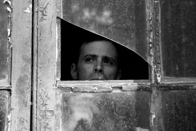 Portrait of man looking through window