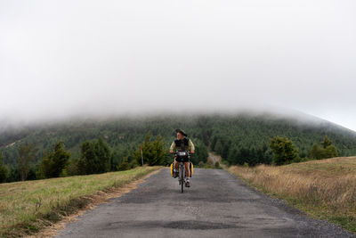 Rear view of man riding bicycle on road