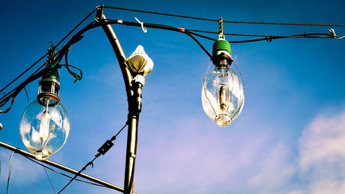 Low angle view of illuminated light bulbs against sky