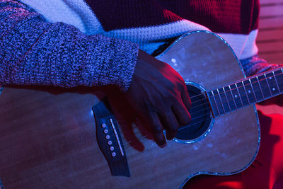 Midsection of man playing guitar