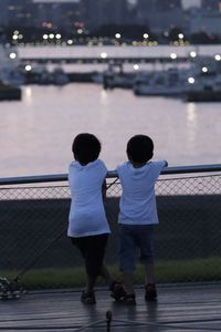 Rear view of siblings standing on bridge over river