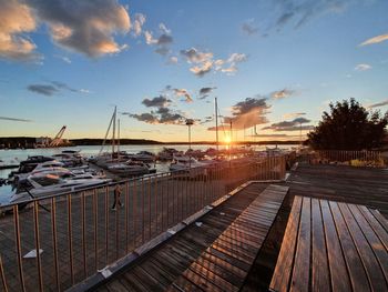 Boats moored at marina against sky during sunset