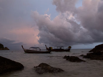 Boats in sea against cloudy sky