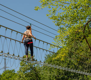 Low angle view of man walking on rope