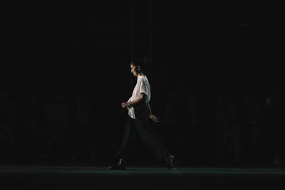 Full length of man standing against black background