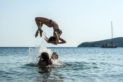 Woman jumping in sea against clear sky