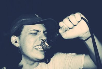 Close-up of man smoking cigarette against black background