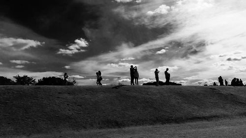 People on landscape against cloudy sky