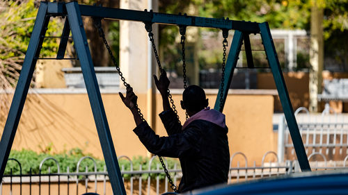 Rear view of man standing on slide at playground