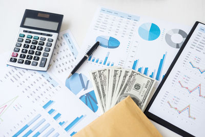 Close-up of documents and currencies with calculator over white background