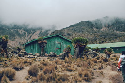 House on field by mountain against sky