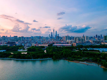 City at waterfront against cloudy sky