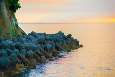 Stack of rocks on sea against sky during sunset