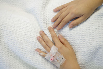 Close-up of woman hand on bed