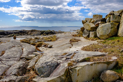 Rocks on shore by sea against sky