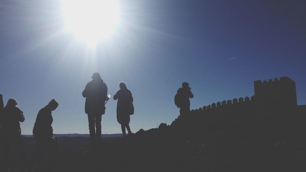 sun, silhouette, sunlight, sunbeam, clear sky, lens flare, sky, sunset, men, low angle view, copy space, lifestyles, leisure activity, standing, outdoors, nature, sunny, blue, person