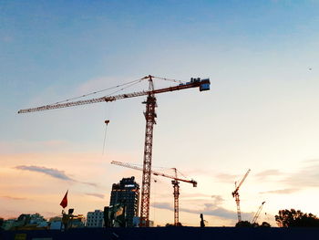 Low angle view of crane at construction site against sky