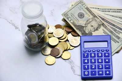 High angle view of coins on paper currencies on table