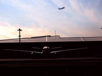 Airplane flying over building against sky