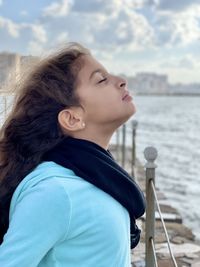 Profile of a young girl taking a deep breath of fresh air by the sea