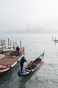 Rear view of men on gondola at san giorgio maggiore during foggy weather