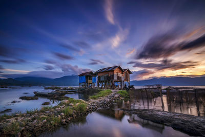 Buildings by sea against sky at sunset