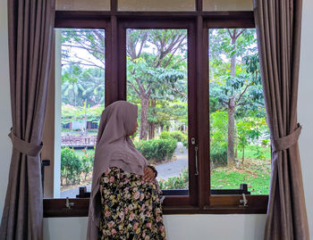 Side view of pregnant woman looking away through window