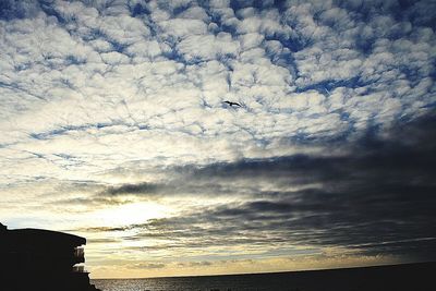 Silhouette of buildings against cloudy sky