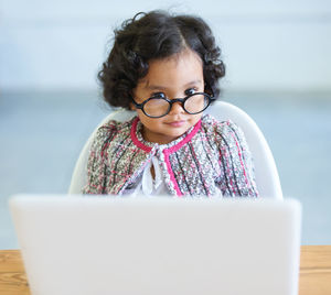 Portrait of cute girl sitting by laptop