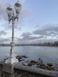 Street light by river against buildings in city