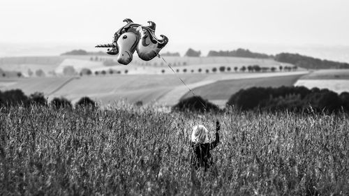 Rear view of girl holding balloon standing on field