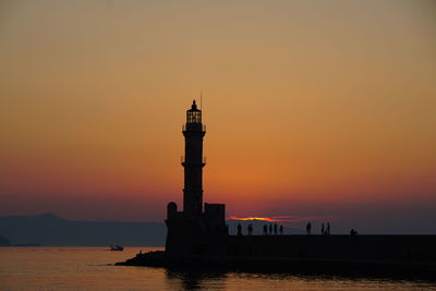 Silhouette of lighthouse at seaside during sunset