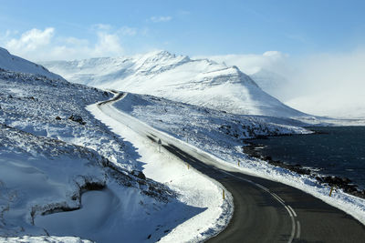 Snowy road with volcanic mountains in wintertime, iceland
