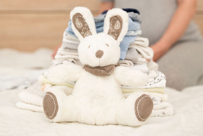 Pile of baby clothes, rabbit and pregnant woman on a bed