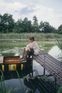 Woman sitting on a wooden pier near the boat