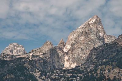 Low angle view of rocks against cloudy sky