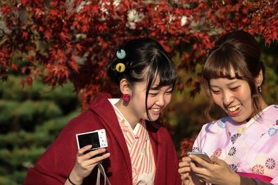 Smiling young woman using mobile phone outdoors