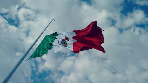 Low angle view of red flag against cloudy sky