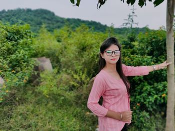 Portrait of young woman standing by plants