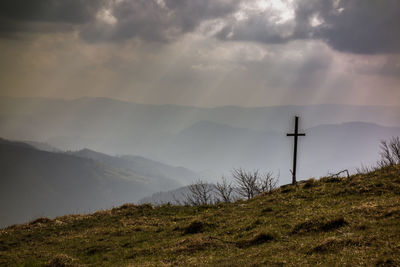 Cross on mountain against sky