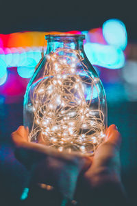 Close-up of hand holding illuminated light in glass jar