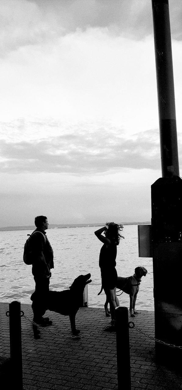 SILHOUETTE PEOPLE ON SHORE AGAINST SEA