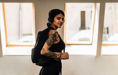 Portrait of smiling young woman while standing at gym