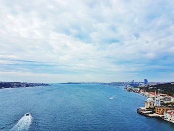 Boats sailing in sea against cloudy sky