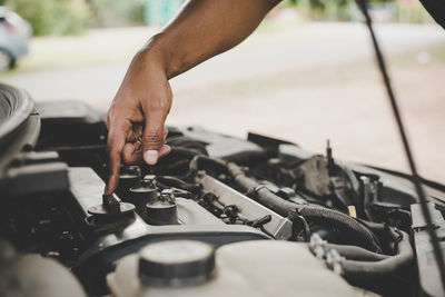 Cropped hand of man repairing engine of car